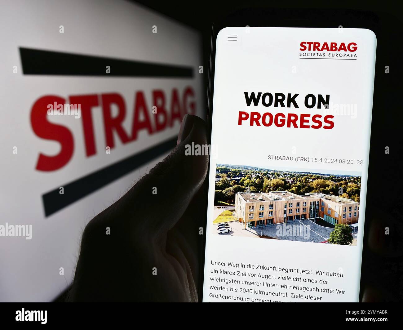 Stuttgart, Allemagne, 04-15-2024 : personne tenant un téléphone portable avec la page web de l'entreprise de construction autrichienne Strabag se devant le logo de l'entreprise. Concentrez-vous sur Banque D'Images