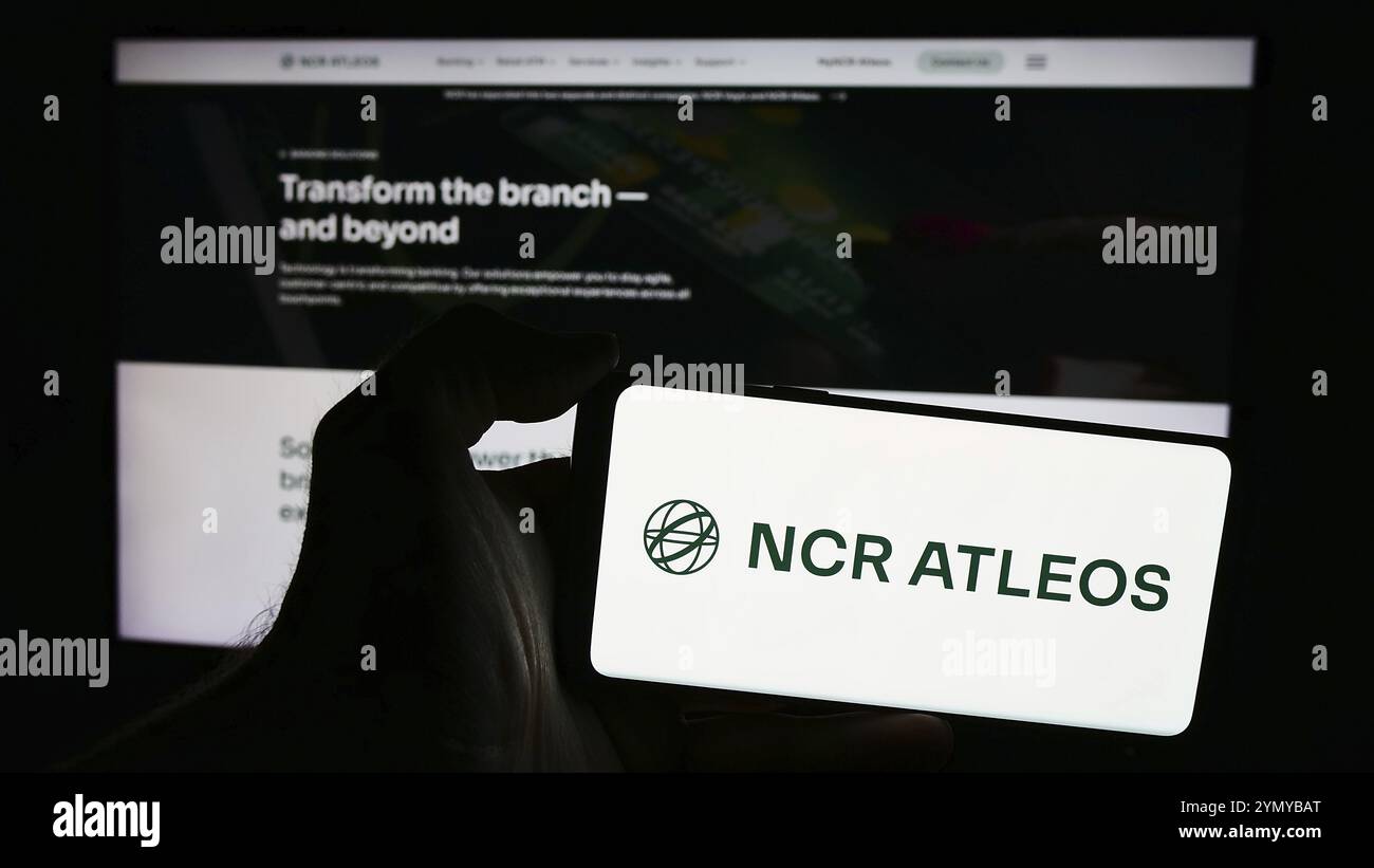 Stuttgart, Allemagne, 05 29 2024 : personne tenant un smartphone avec le logo de la société américaine de services financiers NCR Atleos Corporation devant le site Web. Mise au point Banque D'Images