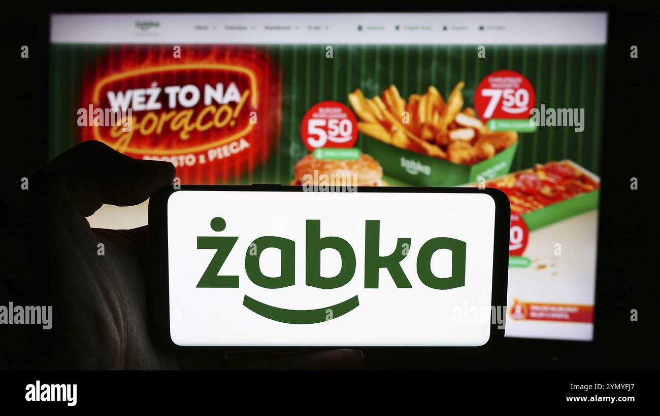 Stuttgart, Allemagne, 07-16-2024 : personne tenant un téléphone portable avec le logo de la société polonaise de vente au détail Zabka Polska sp. z o.o. devant la page web de l'entreprise. Focu Banque D'Images