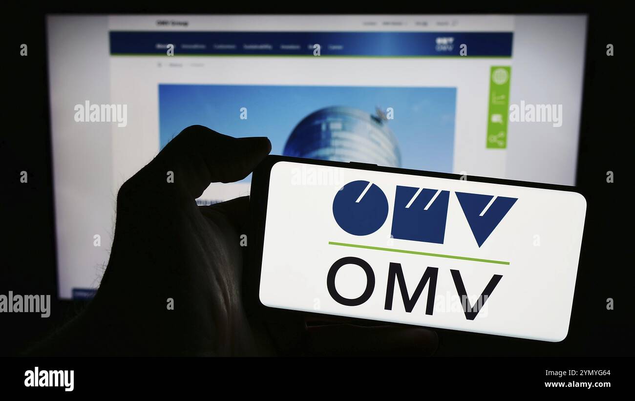 Stuttgart, Allemagne, 03-16-2024 : personne tenant un téléphone portable avec le logo de la compagnie pétrolière et gazière autrichienne OMV Aktiengesellschaft devant la page web de l'entreprise Banque D'Images
