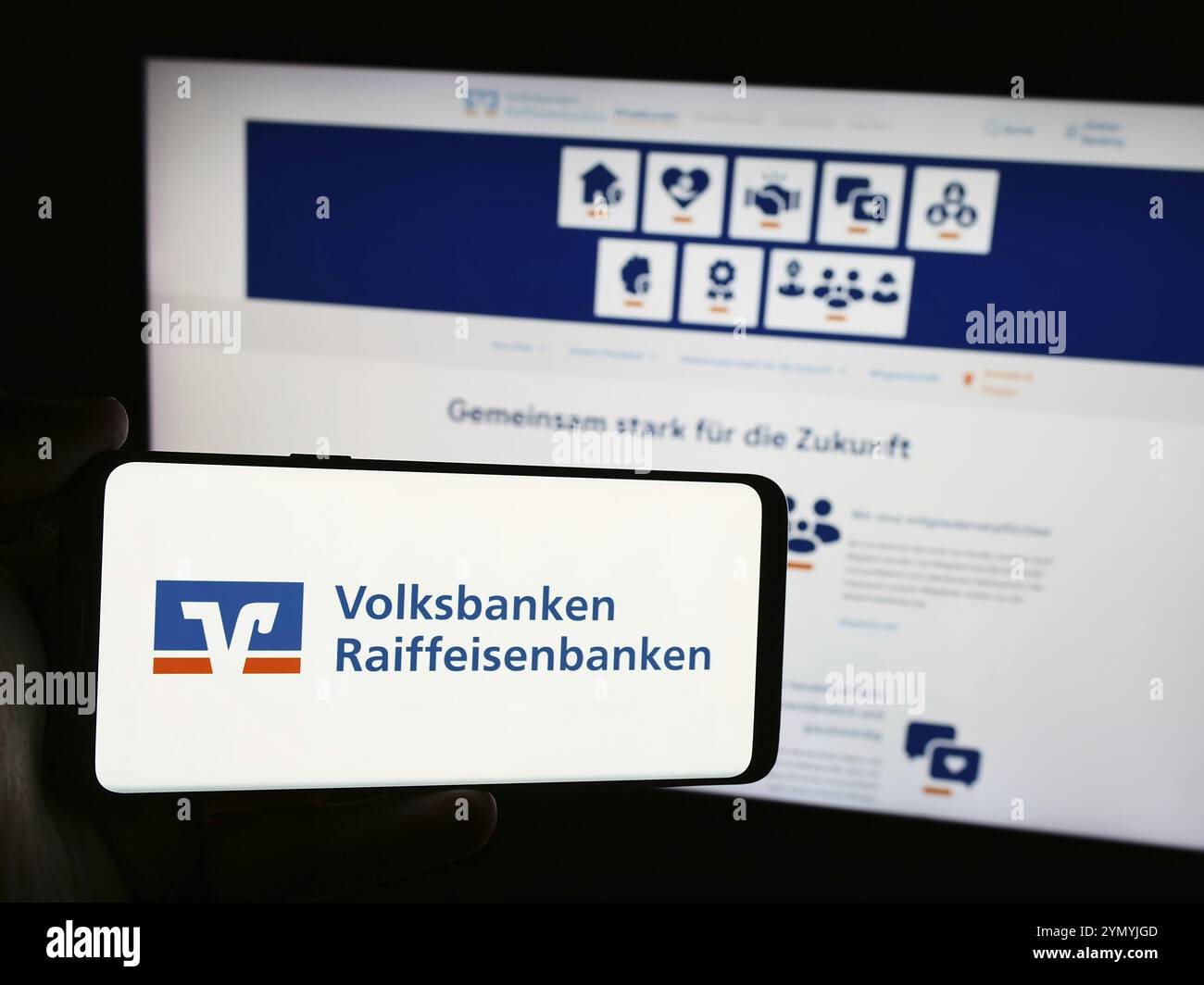 Stuttgart, Allemagne, 07-15-07 2024 : personne tenant un téléphone portable avec le logo du réseau bancaire allemand Volksbanken Raiffeisenbanken devant la page web. FOC Banque D'Images