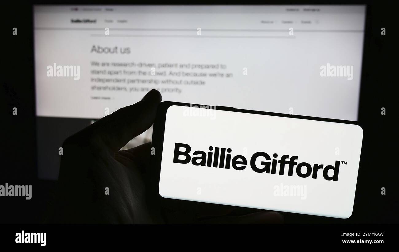 Stuttgart, Allemagne, 03-17-03 2024 : personne tenant un smartphone avec le logo de la société de gestion de placements britannique Baillie Gifford Co. en face du site. Banque D'Images