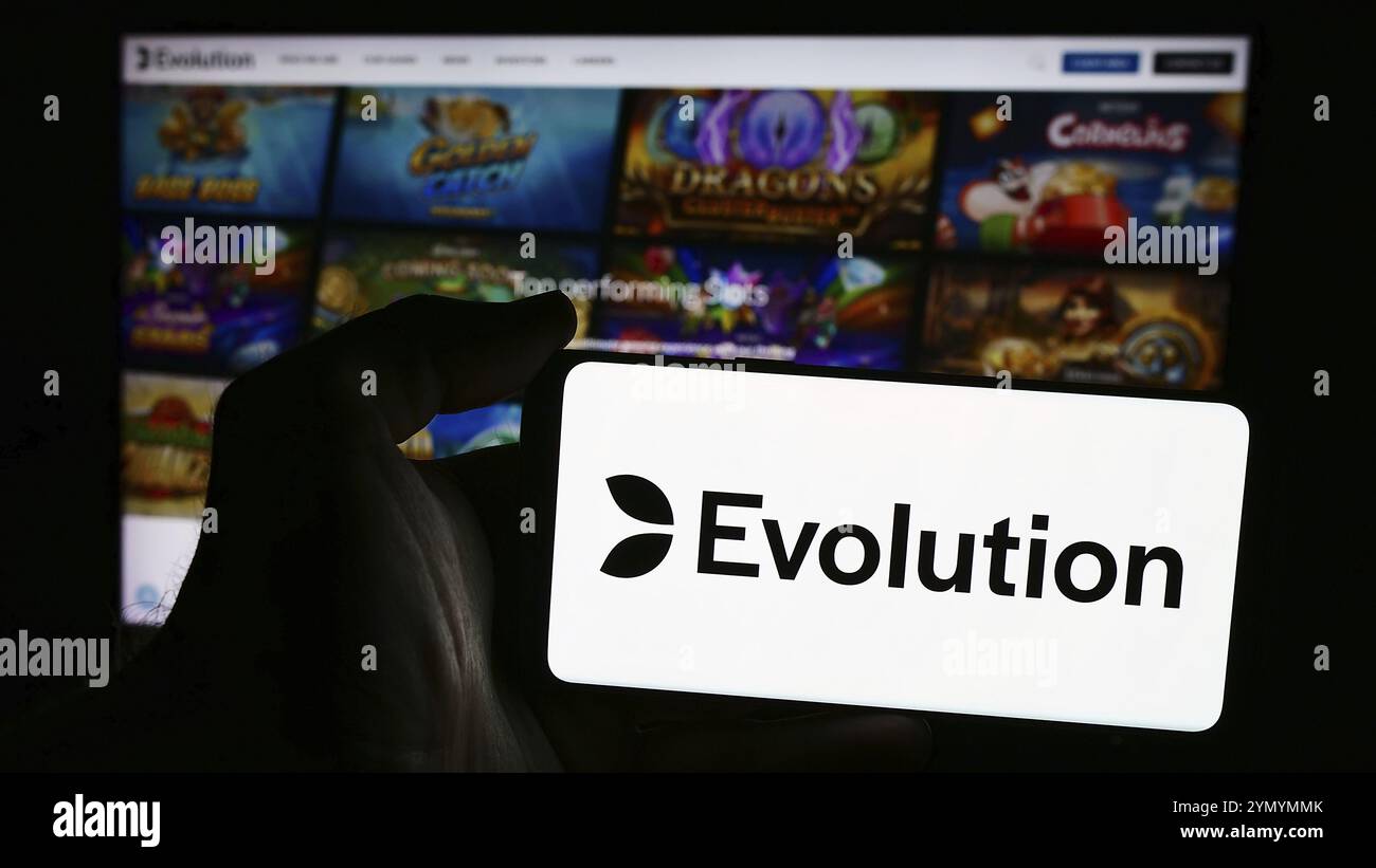 Stuttgart, Allemagne, 07-21-2024 : personne tenant un téléphone portable avec le logo de la société suédoise de technologie de jeu Evolution AB devant le web d'affaires pag Banque D'Images