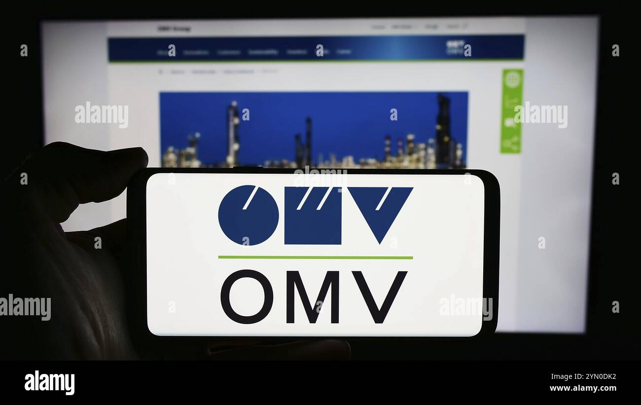 Stuttgart, Allemagne, 03-16-03 2024 : personne tenant un smartphone avec le logo de la société pétrolière et gazière autrichienne OMV Aktiengesellschaft devant le site web. Mise au point Banque D'Images