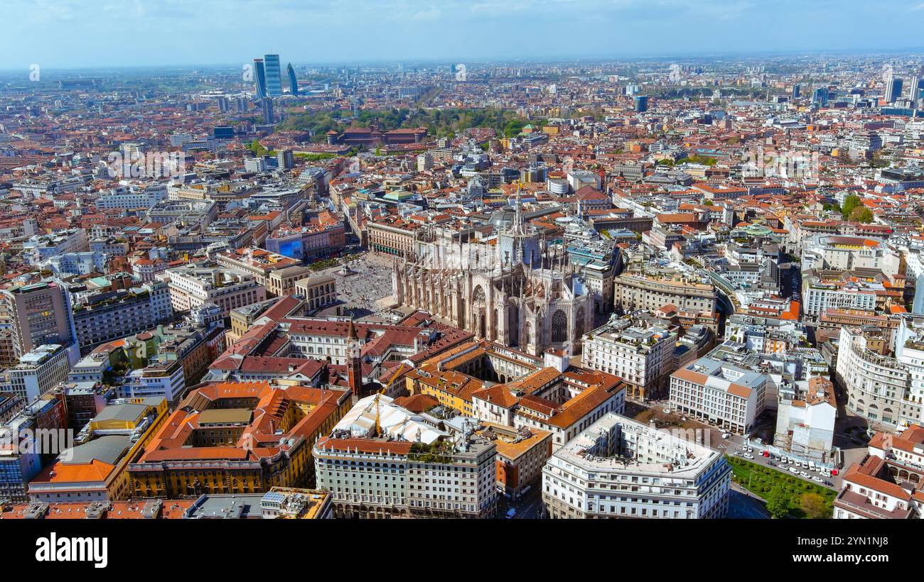 Vue aérienne à couper le souffle de l'emblématique cathédrale Duomo de Milan entourée d'un paysage urbain animé, mettant en valeur l'architecture historique et la vie urbaine sous-jacente Banque D'Images