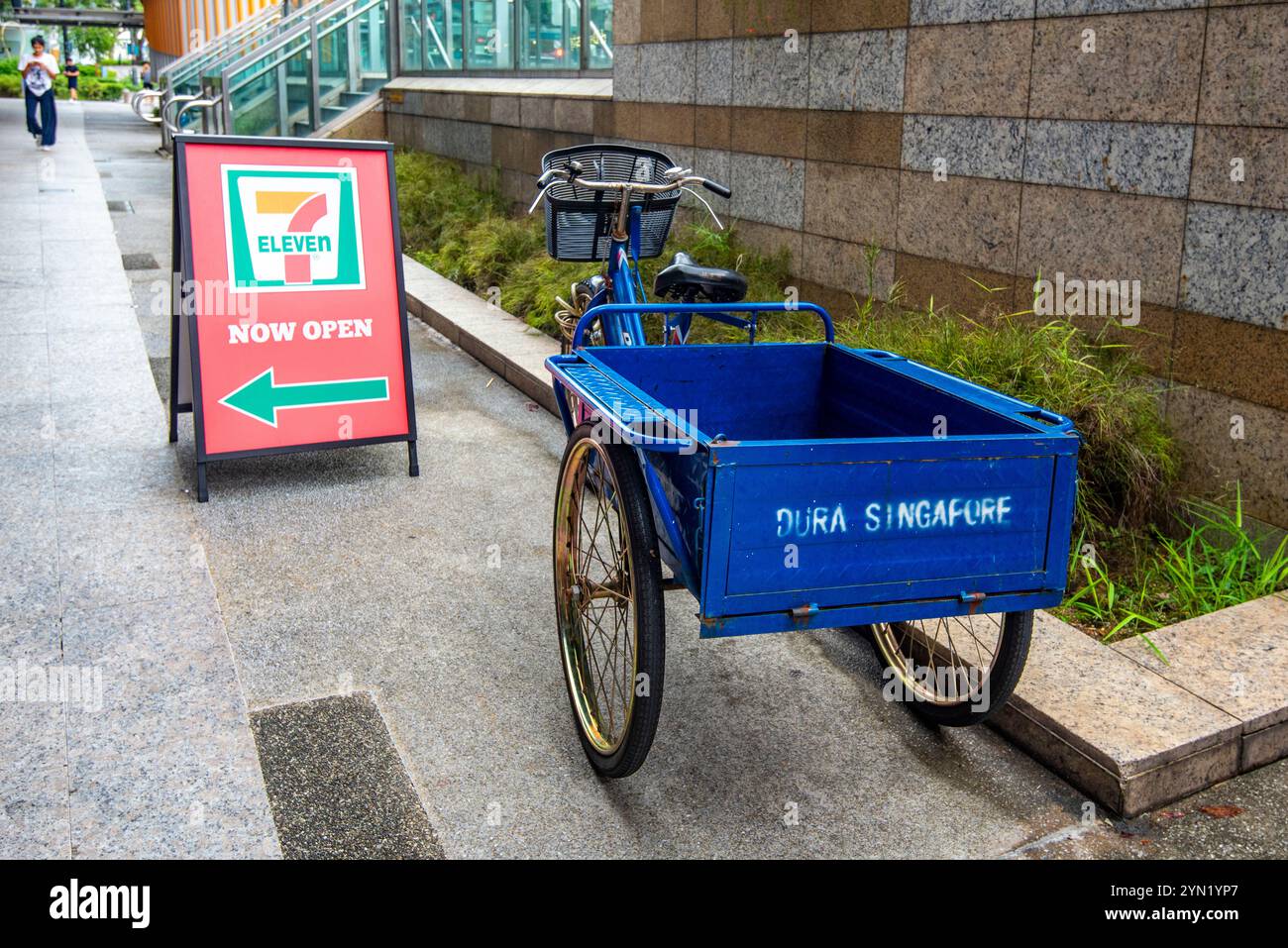 Un vélo de livraison local et une remorque garés devant un magasin 7-Eleven à Singapour Banque D'Images