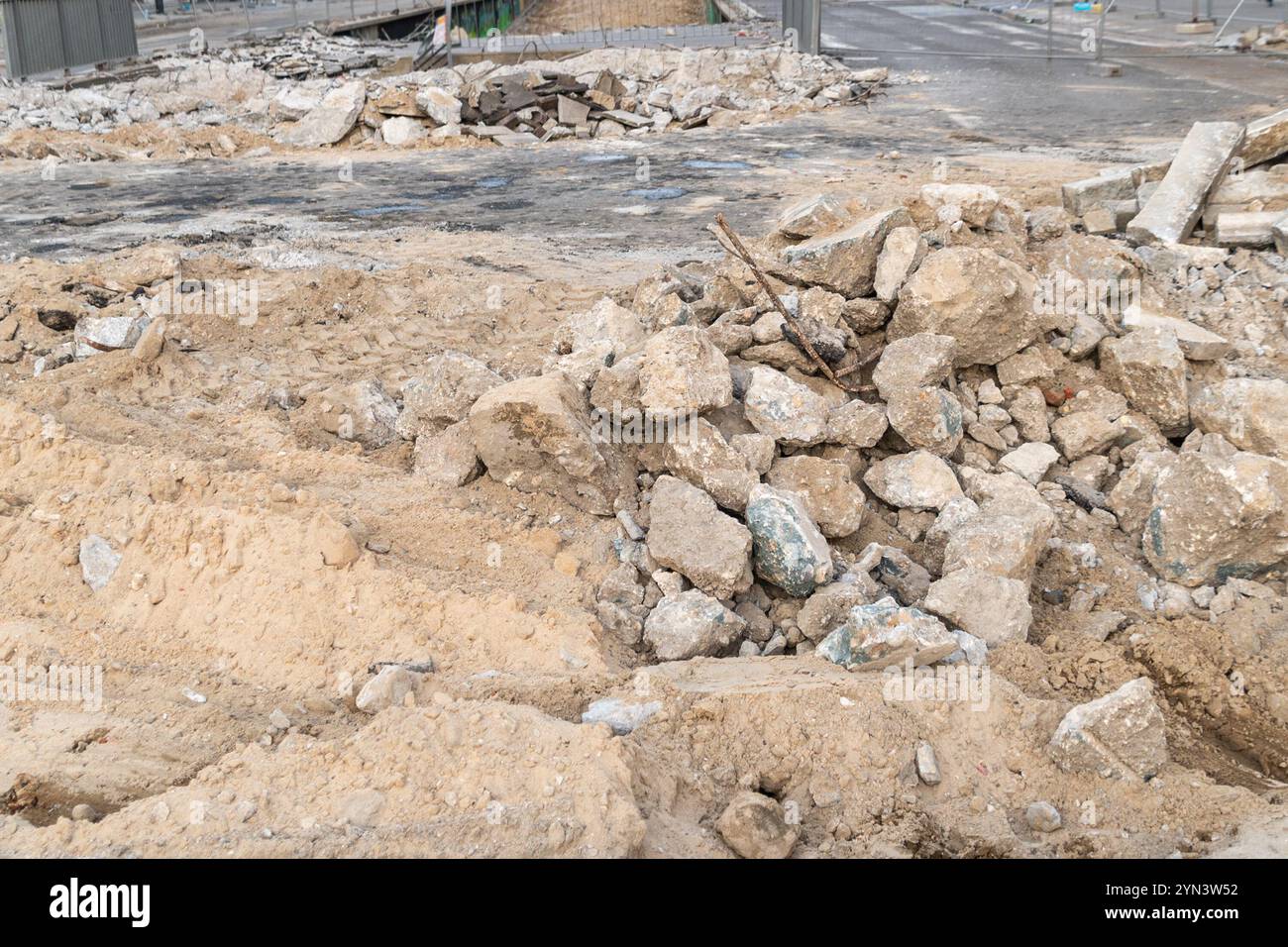 Un chantier de construction avec un tas de gravats et de sable, avec des morceaux de béton cassés et des barres d'armature exposées. L'arrière-plan montre un Ar partiellement démoli Banque D'Images