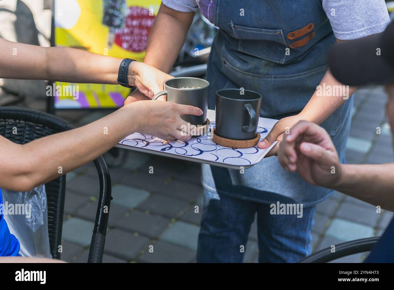 Serveuse servant du café chaud frais dans un café en plein air. Banque D'Images