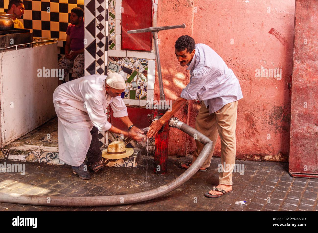 Deux hommes se lavent les mains à une bouche d'incendie dans la médina de Marrakech Banque D'Images