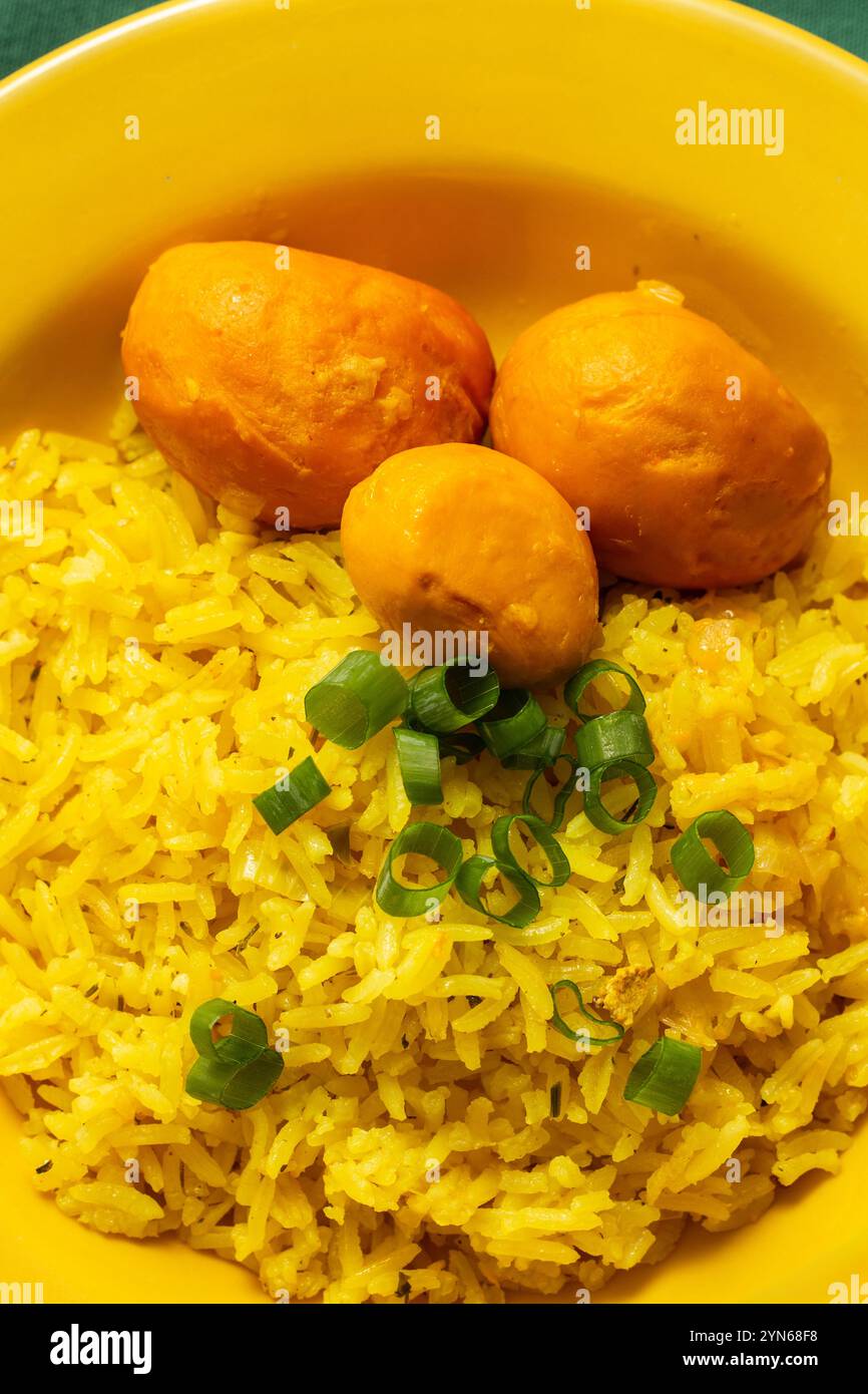 Goiania, Goias, Brésil – 24 novembre 2024 : image verticale d’une plaque jaune remplie de riz avec du pequi et de la ciboulette hachée, sur une doublure verte. Banque D'Images