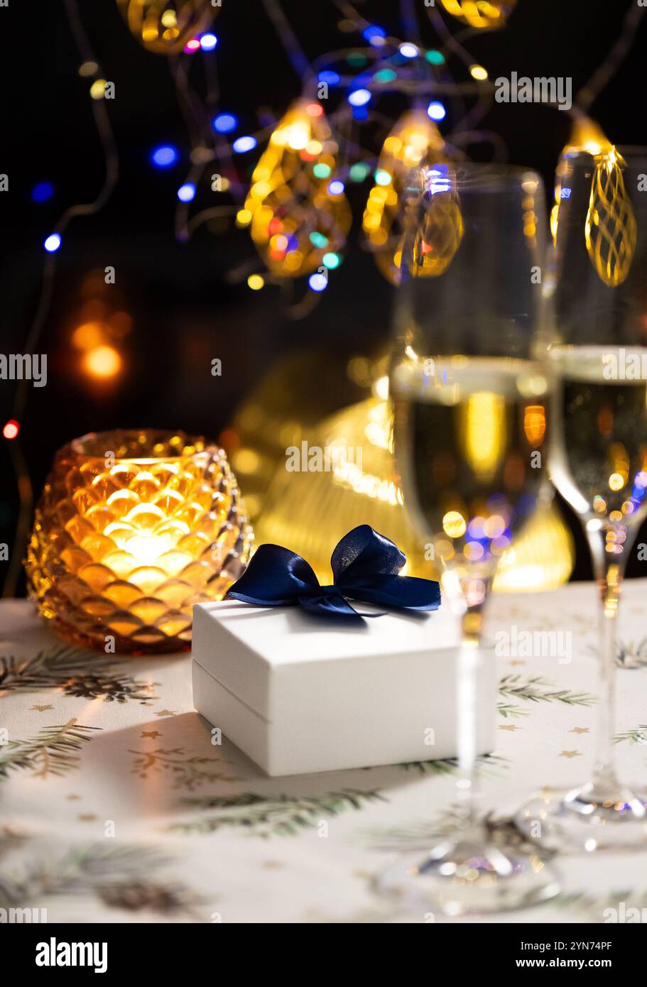 concept de célébration de noël et du nouvel an, verres de champagne sur fond de bougies et de guirlandes colorées, ambiance traditionnelle chaleureuse à la maison Banque D'Images