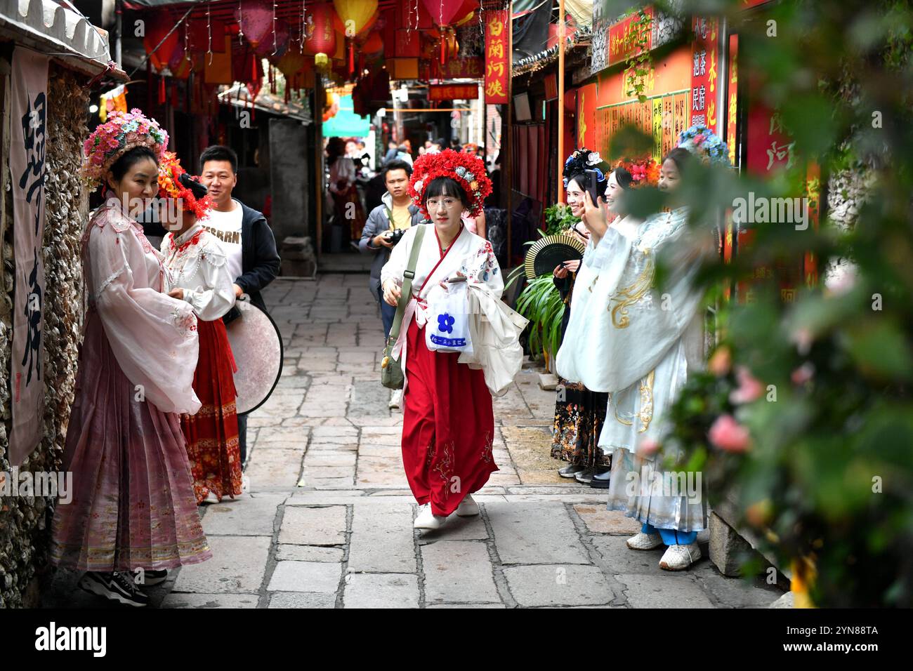 Quanzhou, China.21th novembre 2024. Les touristes portant des « enclos de fleurs en épingle à cheveux » prennent des photos dans le village de Xunpu. Xunpu Village est situé sur la rive nord du port de Quanzhou, le point de départ de l'ancienne route maritime de la soie. Il était autrefois le point de départ d'innombrables navires marchands océaniques et a une histoire de près de mille ans. Il est situé dans la ville de Quanzhou, province du Fujian, le 21 novembre 2024. Crédit : LV Ming/China News Service/Alamy Live News Banque D'Images