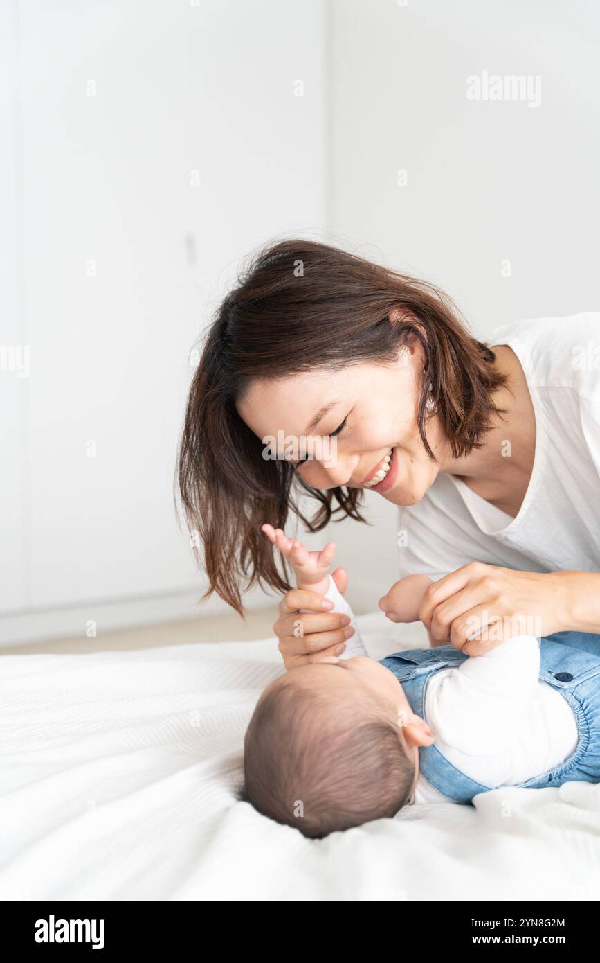 Mère riant en nourrissant son bébé Banque D'Images