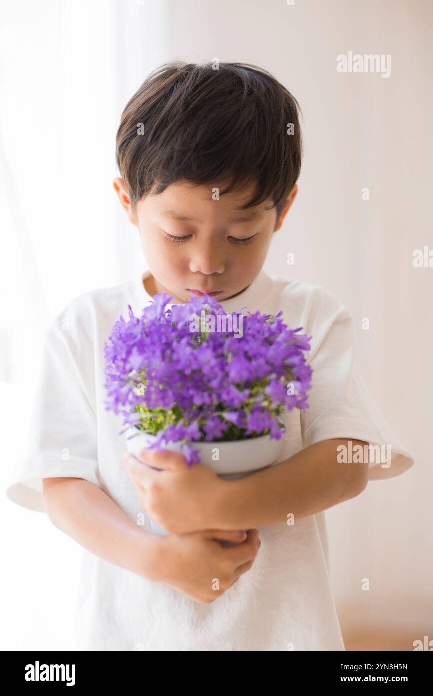 Enfant tenant des fleurs en pot à l'intérieur Banque D'Images