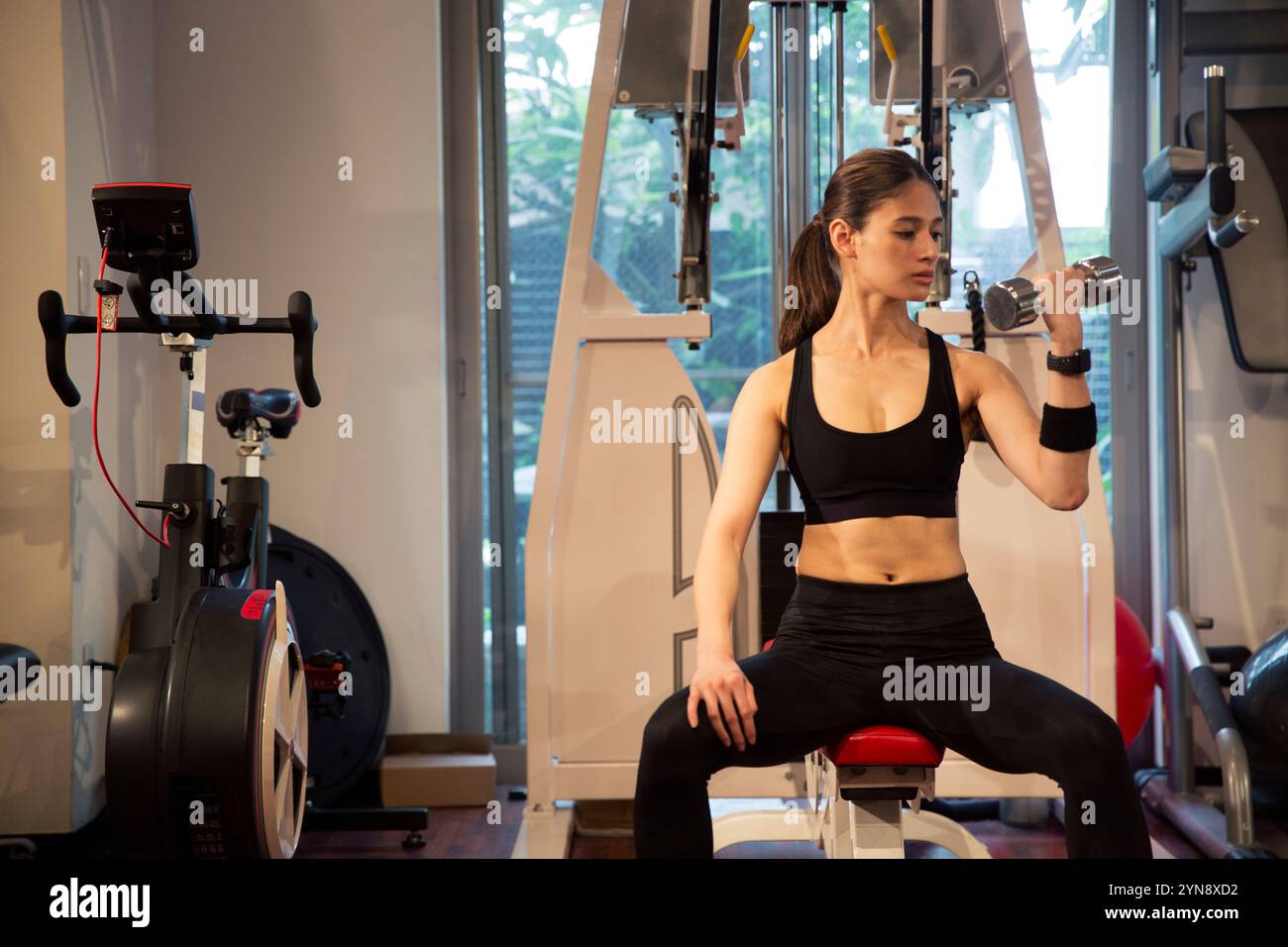 Femme dans sa vingtaine d'années s'entrainant au gymnase Banque D'Images