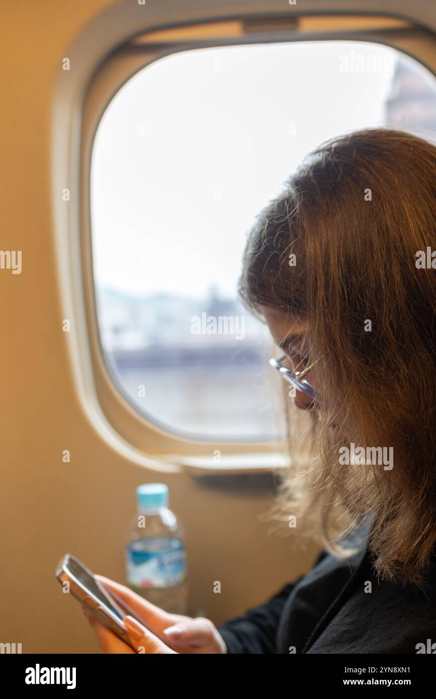 Passager utilisant un smartphone à l'intérieur du train Shinkansen Banque D'Images