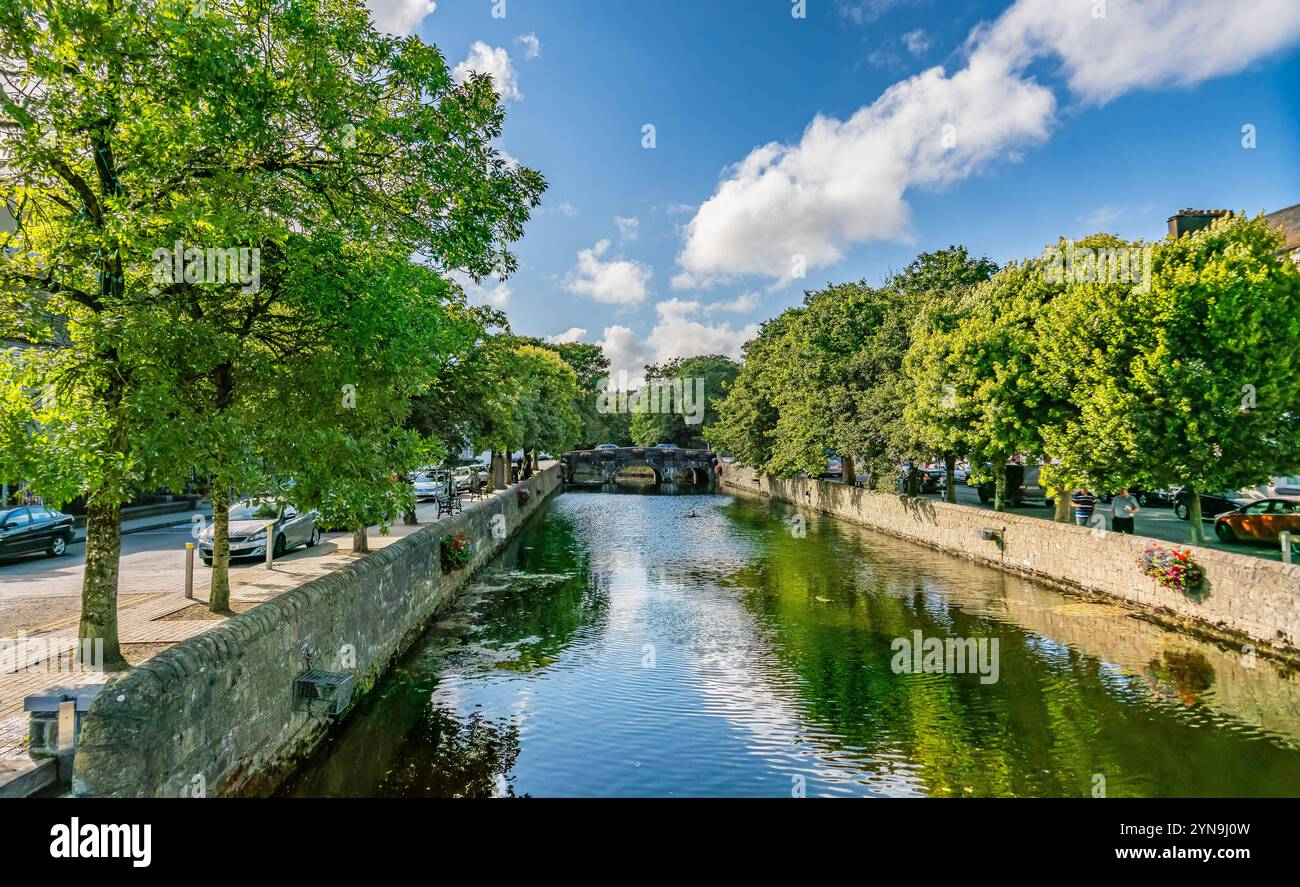 Une scène pittoresque avec un charmant pont de pierre orné de fleurs sur une rivière sereine, situé dans un village européen pittoresque avec archite historique Banque D'Images