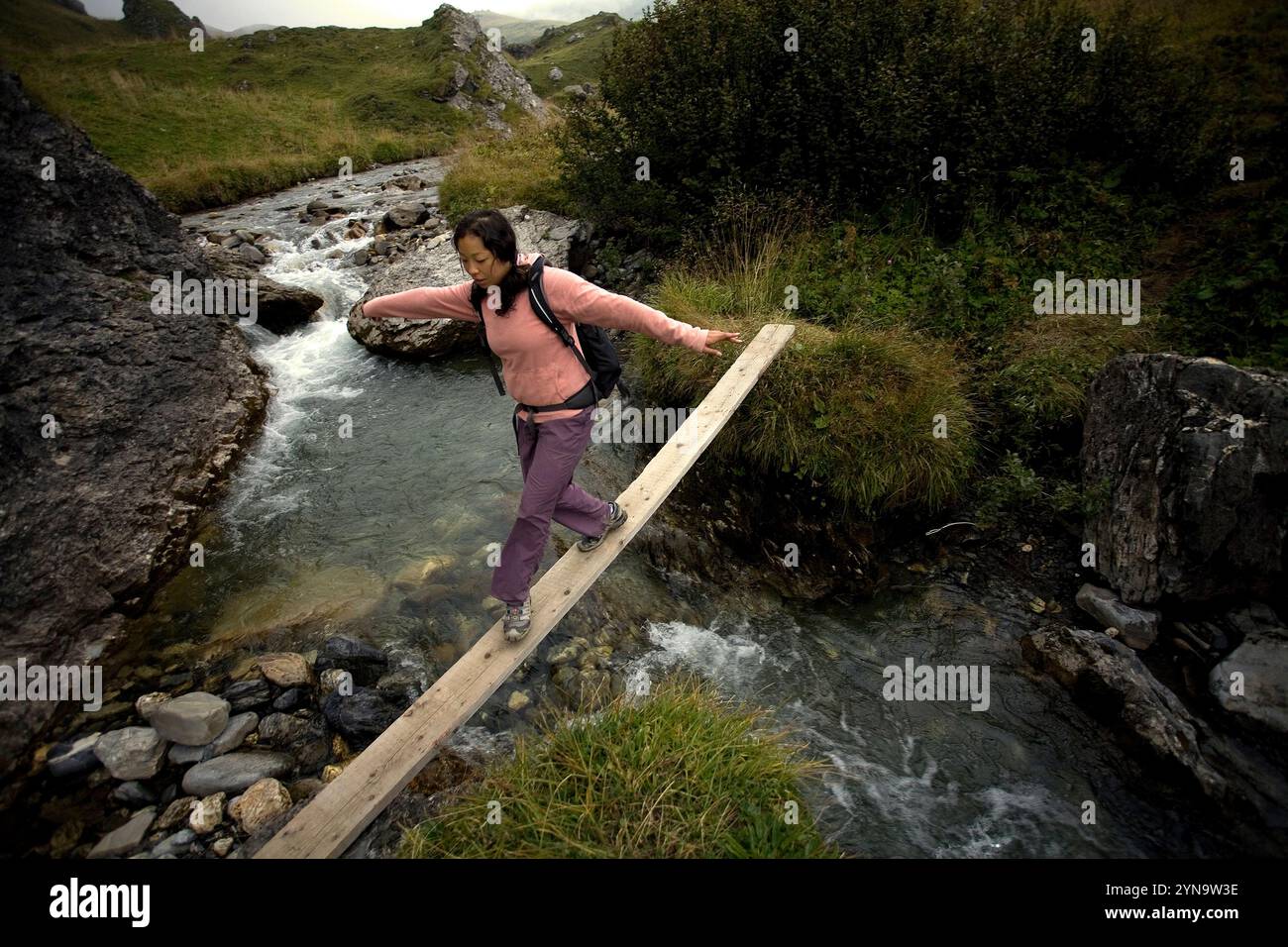 Une fille traversant un pont sur un ruisseau près du col de Roseland en Savoie, France. Banque D'Images