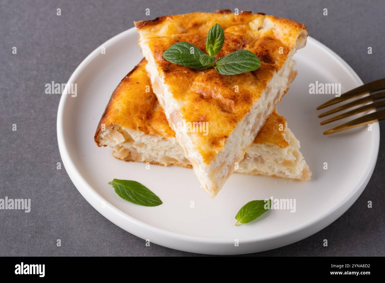 Délicieuse tarte aux pommes maison servie garnie de feuilles de menthe sur une table de cuisine confortable Banque D'Images