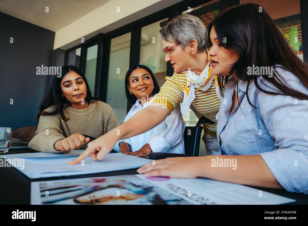 Un enseignant dévoué instruisant les élèves sur une tâche de devoirs, favorisant l'apprentissage et l'engagement dans un environnement de classe diversifié. Banque D'Images