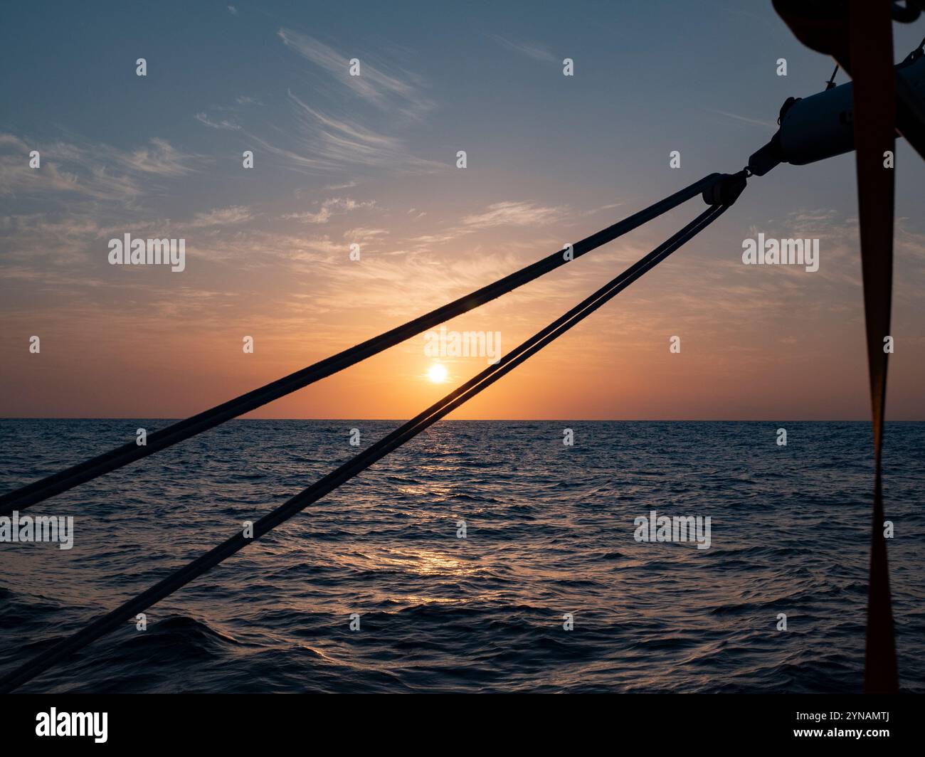 Coucher de soleil sur le golfe de Gascogne en juillet, comme on l'a vu de mon voilier à 150 milles nautiques de la terre. Les lignes pour contrôler la grande voile et une partie du Banque D'Images