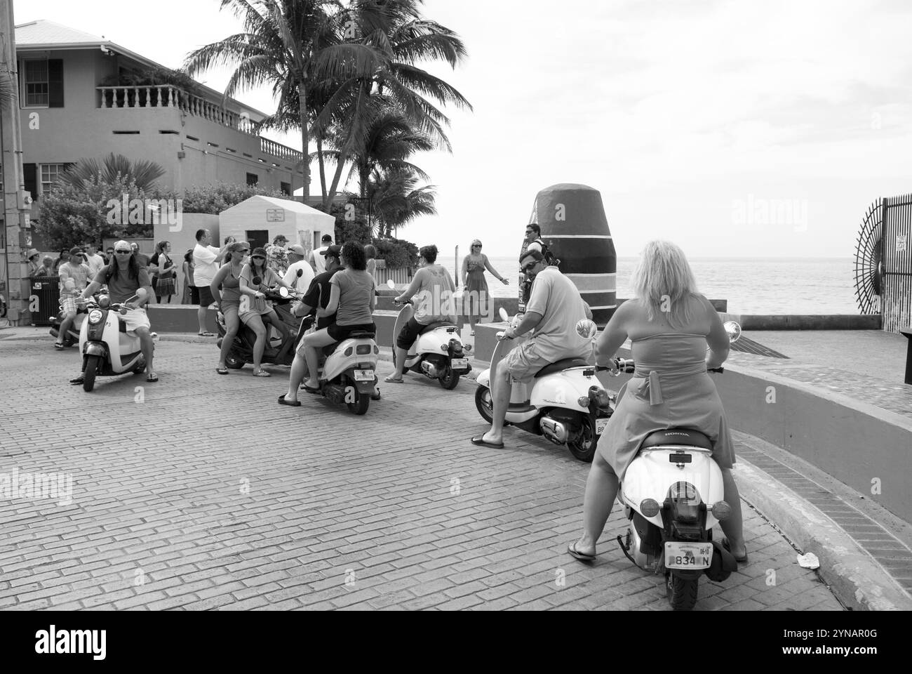 Touristes chevauchant des scooters devant la bouée pointe emblématique la plus méridionale à Key West, Floride, États-Unis. Banque D'Images