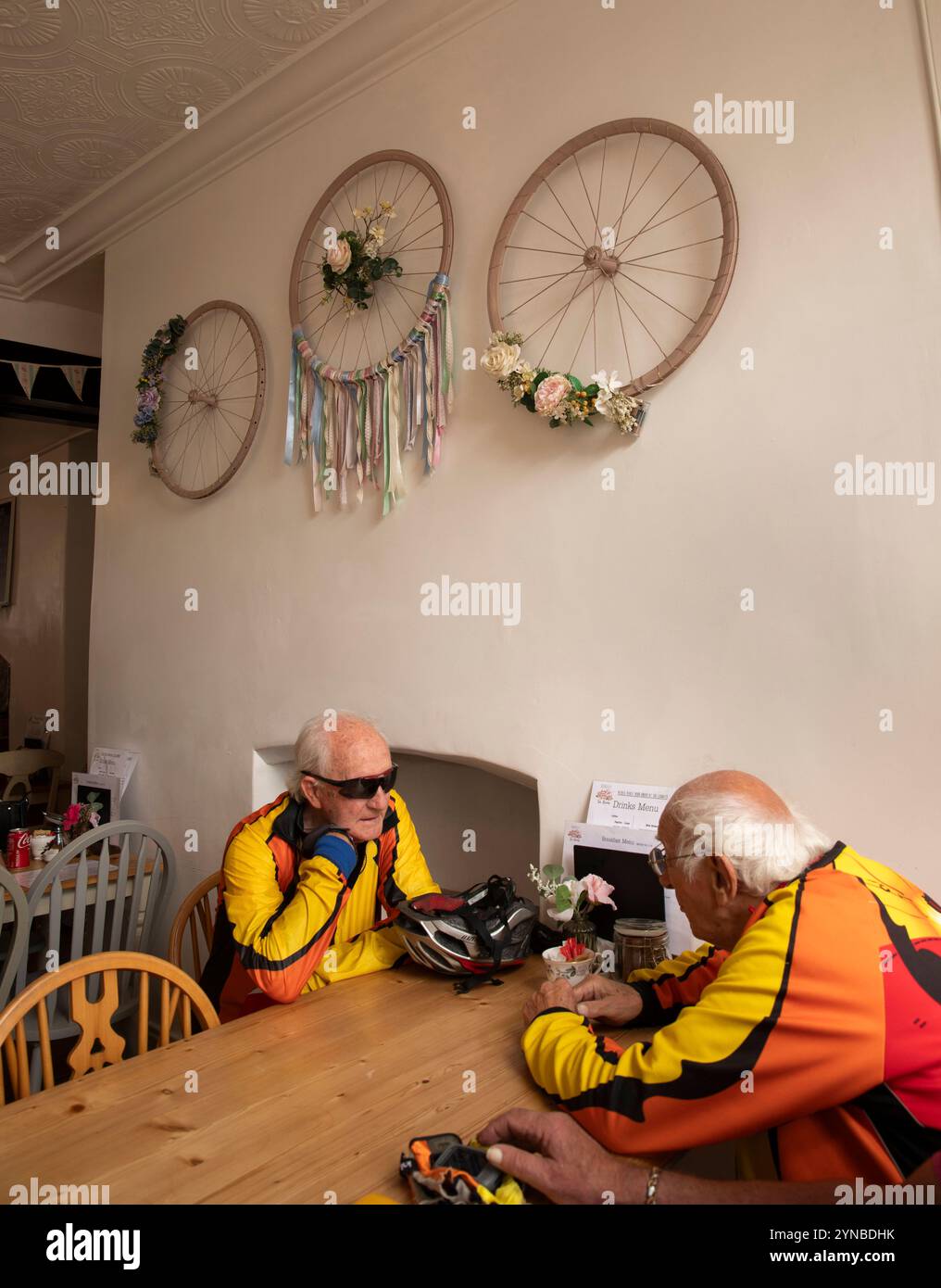 Royaume-Uni, Angleterre, Gloucestershire, Vale of Berkeley, Berkeley, High Street, Old White Hart Inn, intérieur du salon de thé, cyclistes âgés sous la décoration de roue de vélo Banque D'Images