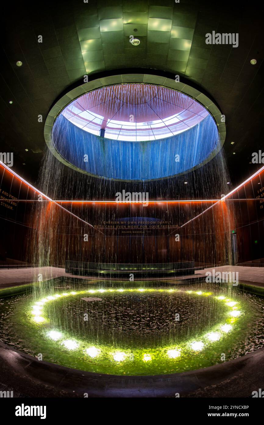 Musée national d'histoire afro-américaine contemplative court Washington DC // WASHINGTON DC — la cour contemplative du musée national d'histoire et de culture afro-américaine présente une fontaine cylindrique tombant d'une lucarne dans une piscine centrale. Conçu par l'architecte Phil Freelon, l'espace comprend des murs en verre Bendheim en bronze caramel avec des noyaux de mailles lumineux. Cet espace de méditation offre aux visiteurs un lieu de réflexion après avoir vu les expositions du musée. Banque D'Images