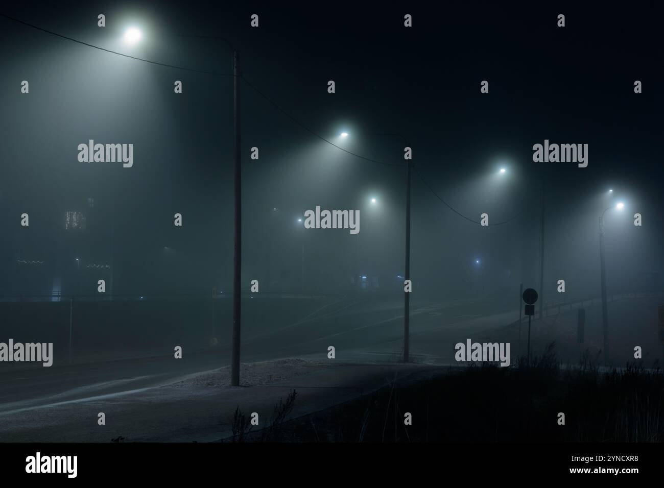 Vue d'une route urbaine vide, bleu nuit foncé, brumeuse et pluvieuse, faible visibilité en raison de la saison. Mauvais temps pluvieux saisonnier, danger d'accident, avertissement Banque D'Images