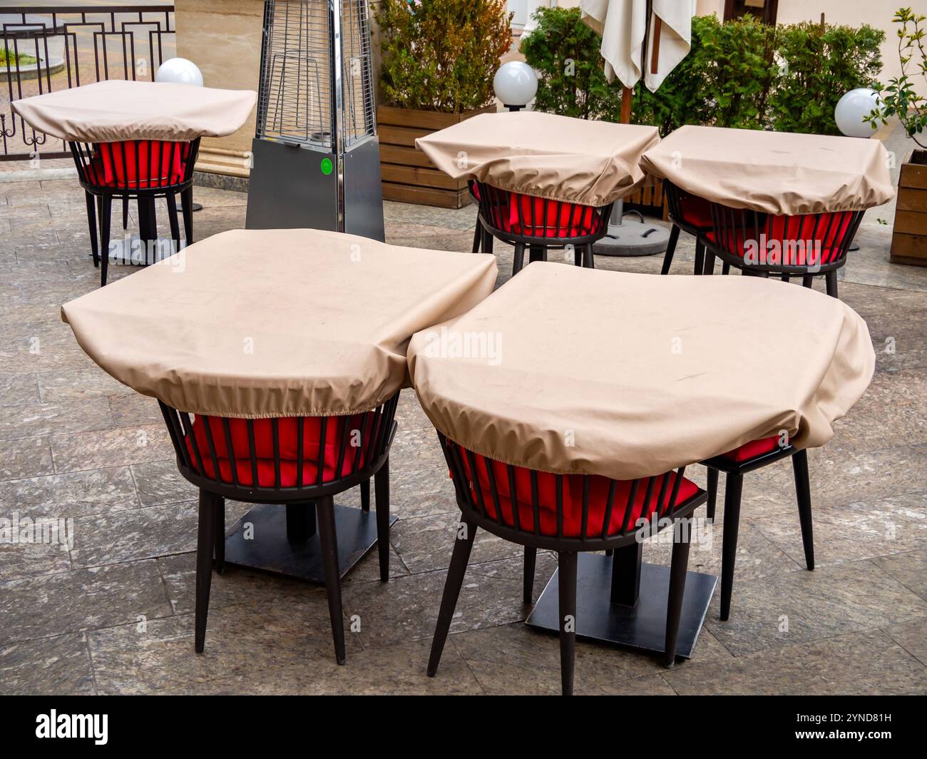 Tables inutilisées dans un café en plein air recouvertes de couvertures Banque D'Images