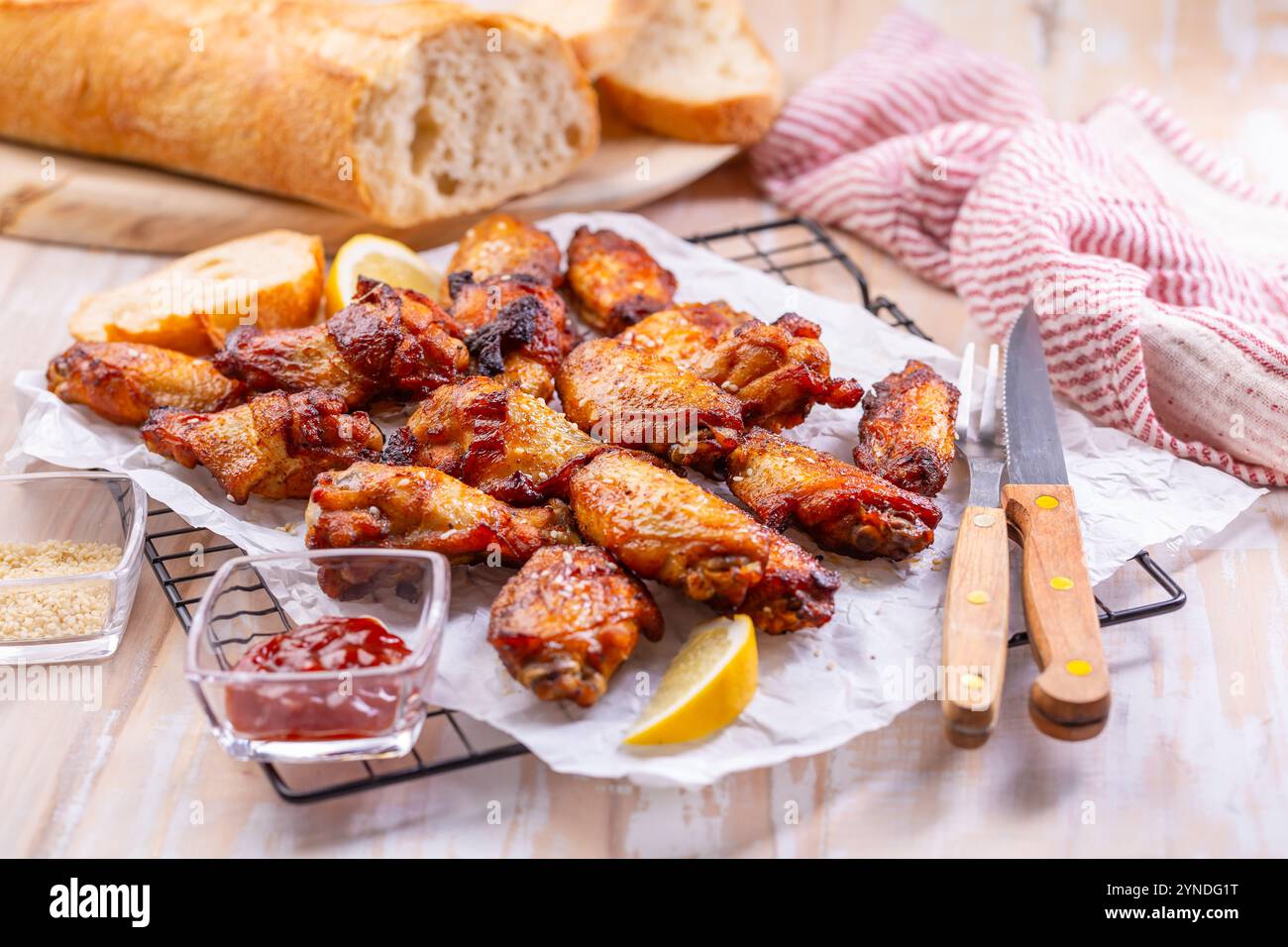Ailes de poulet marinées et grillées avec citron, ail, graines de sésame et baguette fraîche Banque D'Images