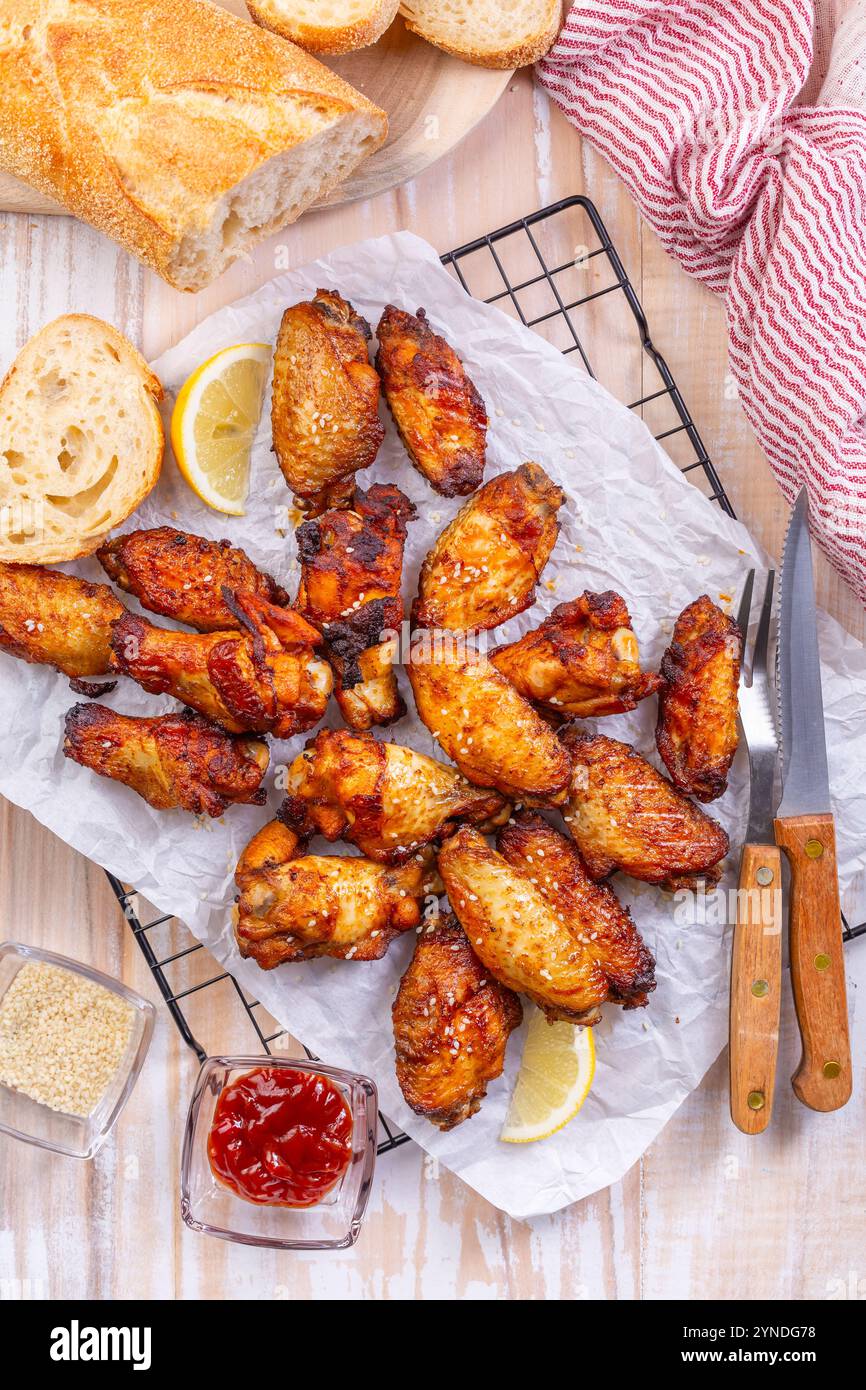 Ailes de poulet marinées et grillées avec citron, ail, graines de sésame et baguette fraîche Banque D'Images