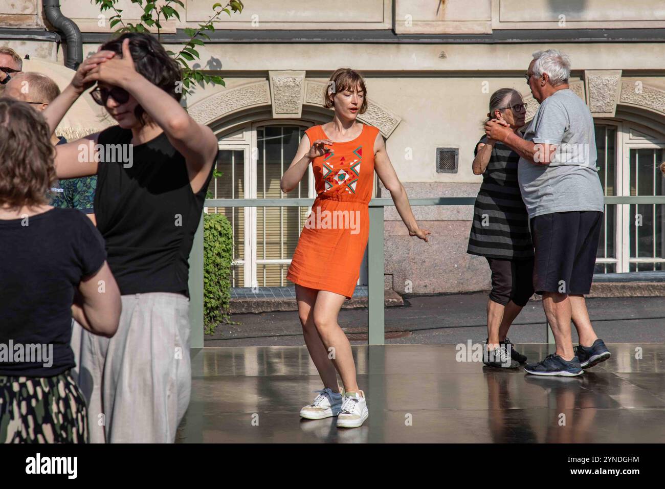 Femme en robe orange dansant à Summer Street Dances sur Design Museum Square dans le quartier Ullanlinna d'Helsinki, Finlande Banque D'Images