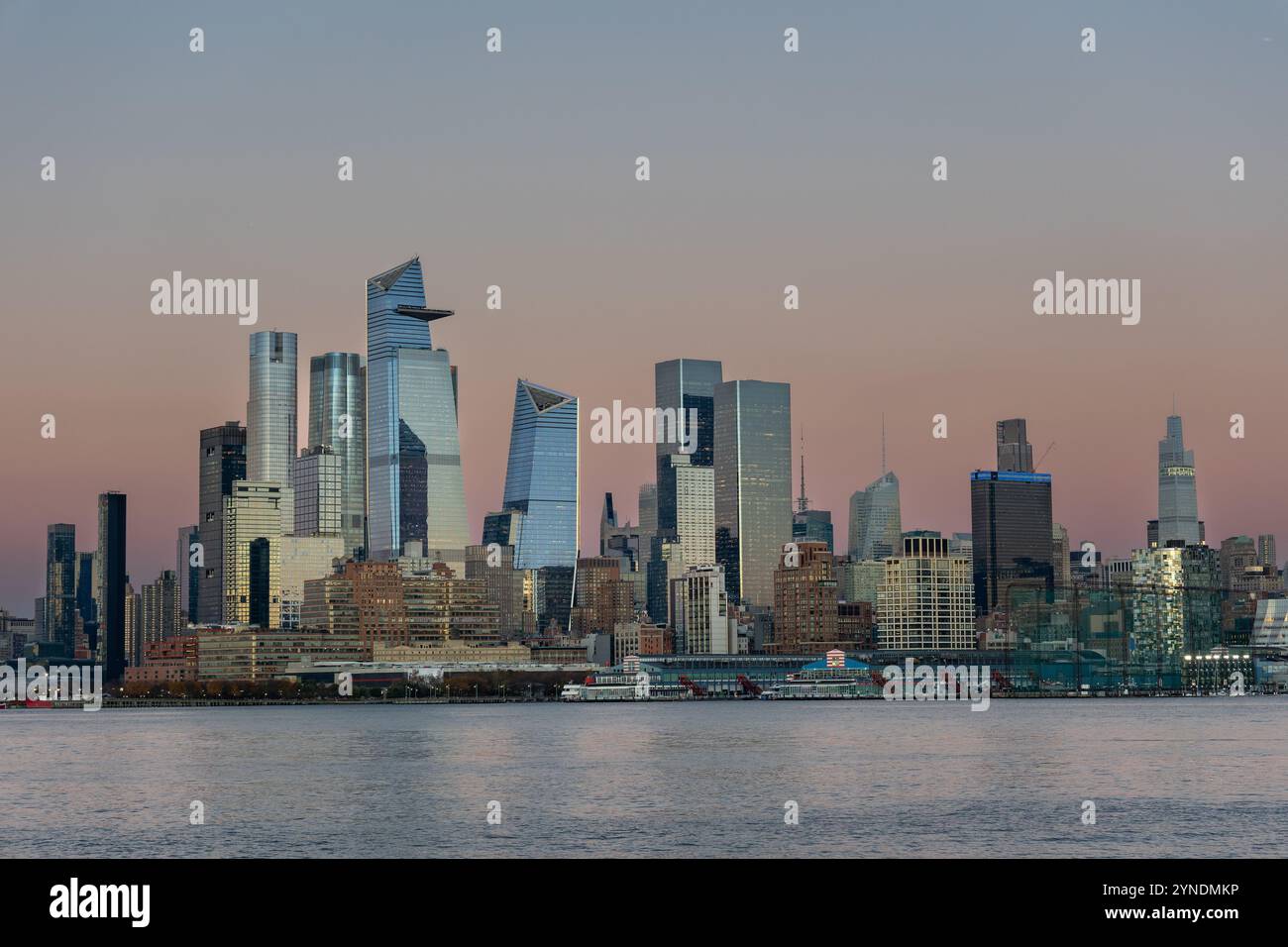 Les superbes gratte-ciel de New York Midtown comprennent de grands bâtiments modernes reflétant les couleurs du crépuscule au coucher du soleil. Le front de mer ajoute un élément serein. Banque D'Images