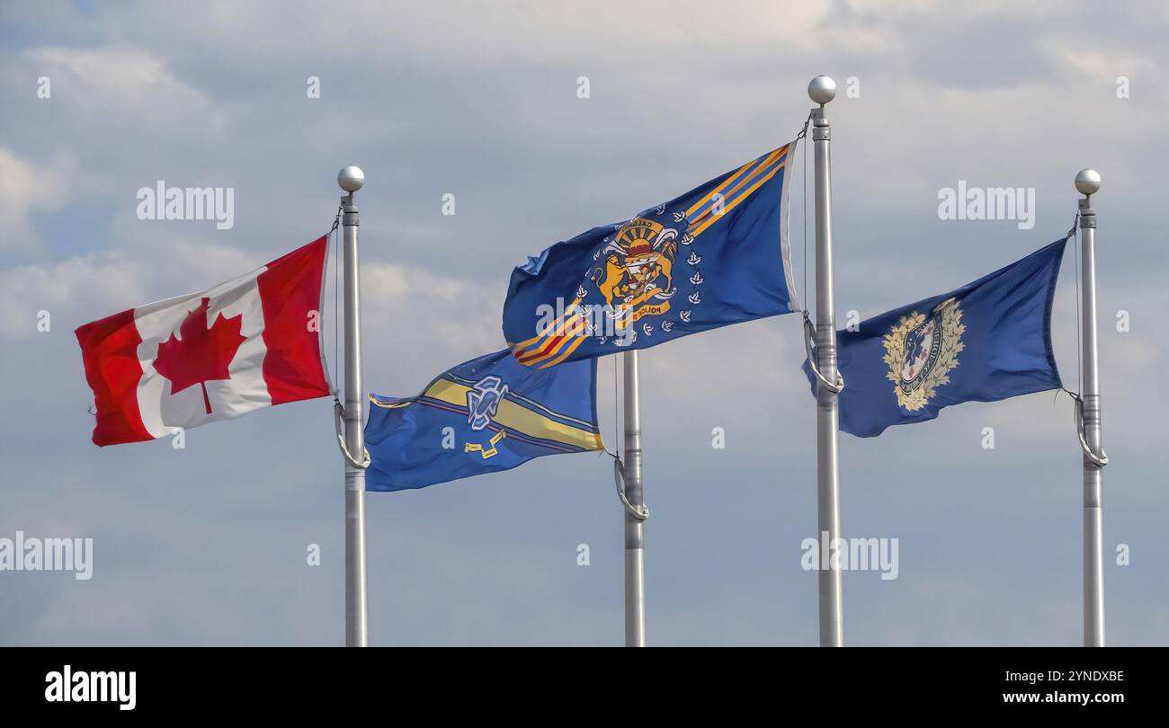 Calgary, Alberta, Canada. 25 juillet 2023. Drapeaux de la police, des pompiers et des services de santé d'urgence portant un drapeau canadien lors d'une journée venteuse Banque D'Images