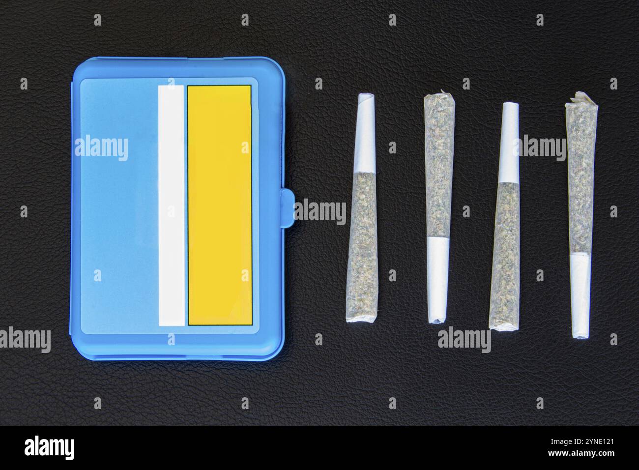 Quatre joints de cannabis légal canadien sur fond de cuir noir. 2 grammes par joint et étui en plastique bleu Banque D'Images