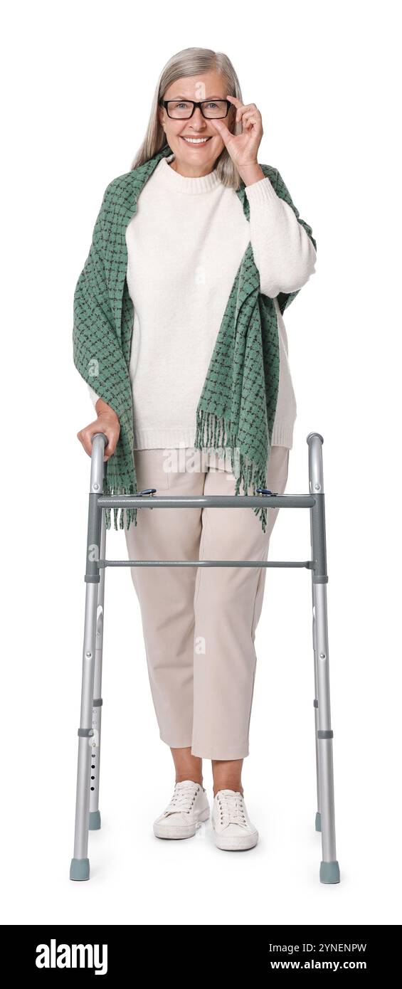 Femme senior utilisant le cadre de marche sur fond blanc Banque D'Images