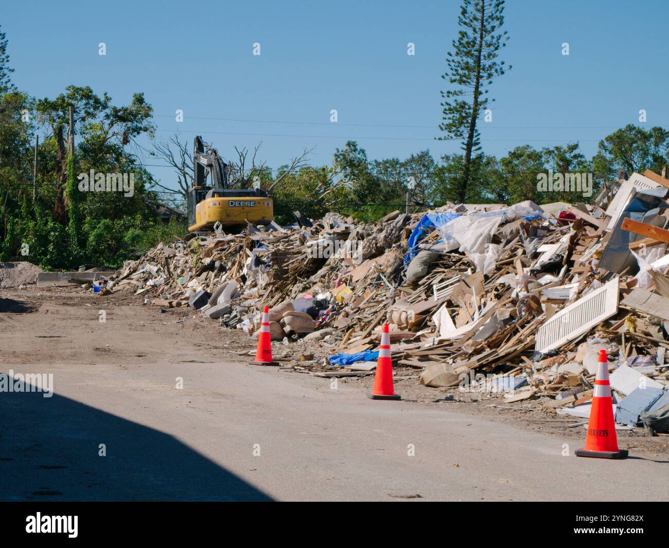 Usage éditorial uniquement le 23 novembre 2024. Gulfport, Floride, États-Unis. Site de collecte des débris endommagés par les tempêtes. Porte intérieure avec cône orange, grue jaune et pieux Banque D'Images