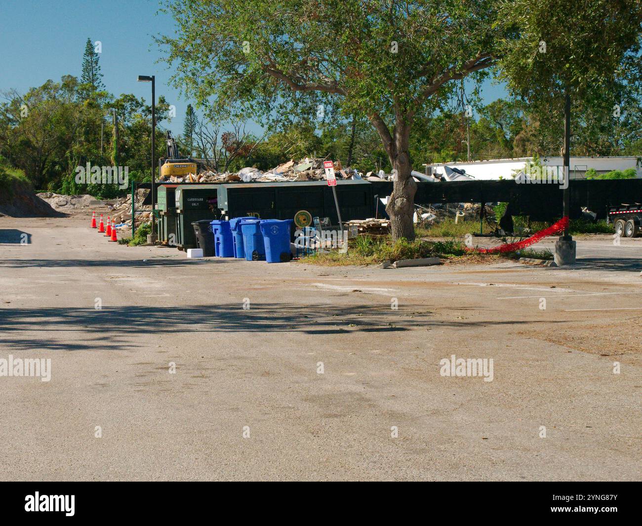 Usage éditorial uniquement le 23 novembre 2024. Gulfport, Floride, États-Unis. Site de collecte des débris endommagés par les tempêtes. Porte d'entrée avec cône orange, benne à ordures verte, bleue Banque D'Images