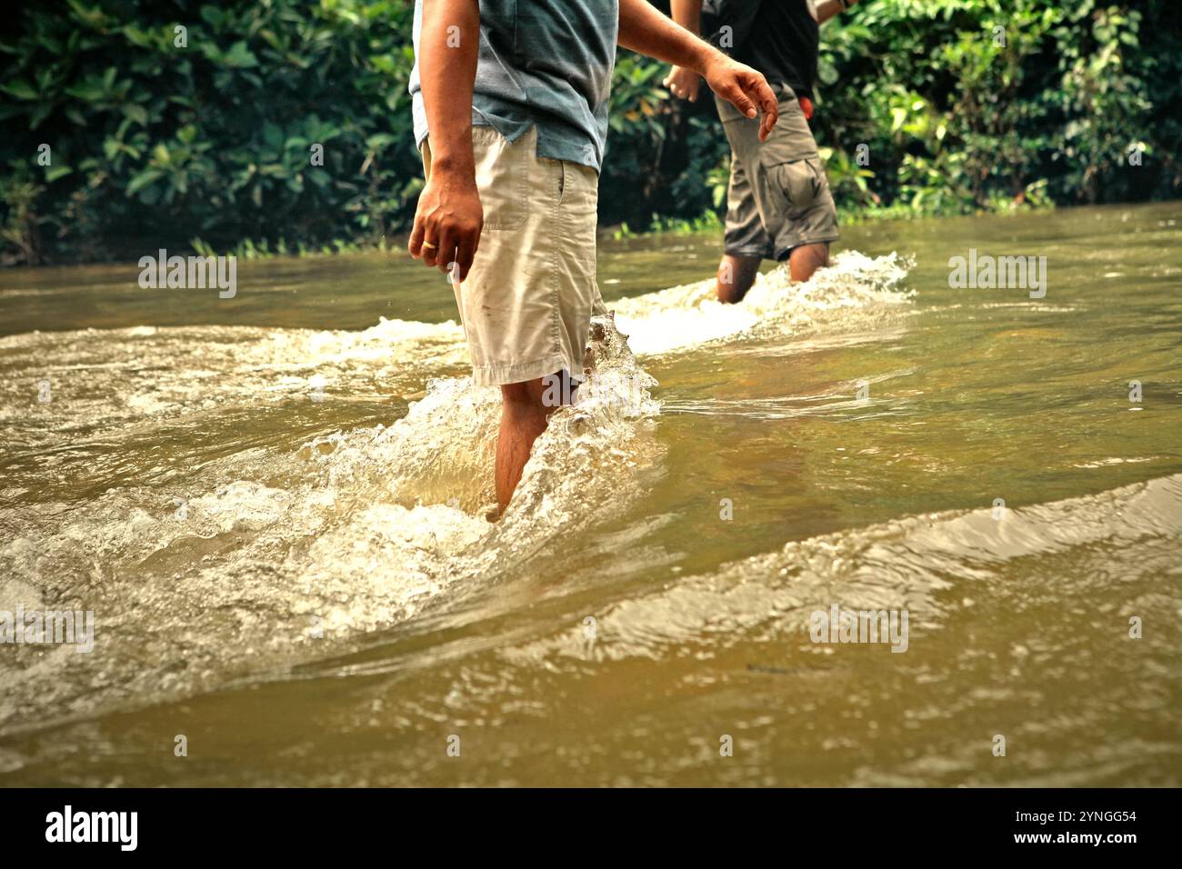 Hommes marchant sur un ruisseau rapide peu profond au milieu de la forêt coutumière de la communauté Dayak IBAN à Sungai Utik, Kapuas Hulu, Kalimantan occidental, Indonésie. Banque D'Images