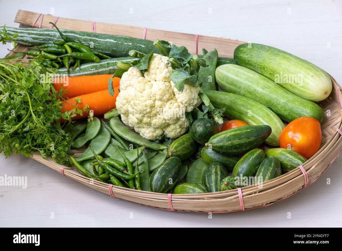 Un kula ou kulo traditionnel tissé en canne de bambou fourré de légumes frais, y compris le chou-fleur, les carottes, le concombre, la gourde de de serpent, feuilles de coriandre, gr Banque D'Images