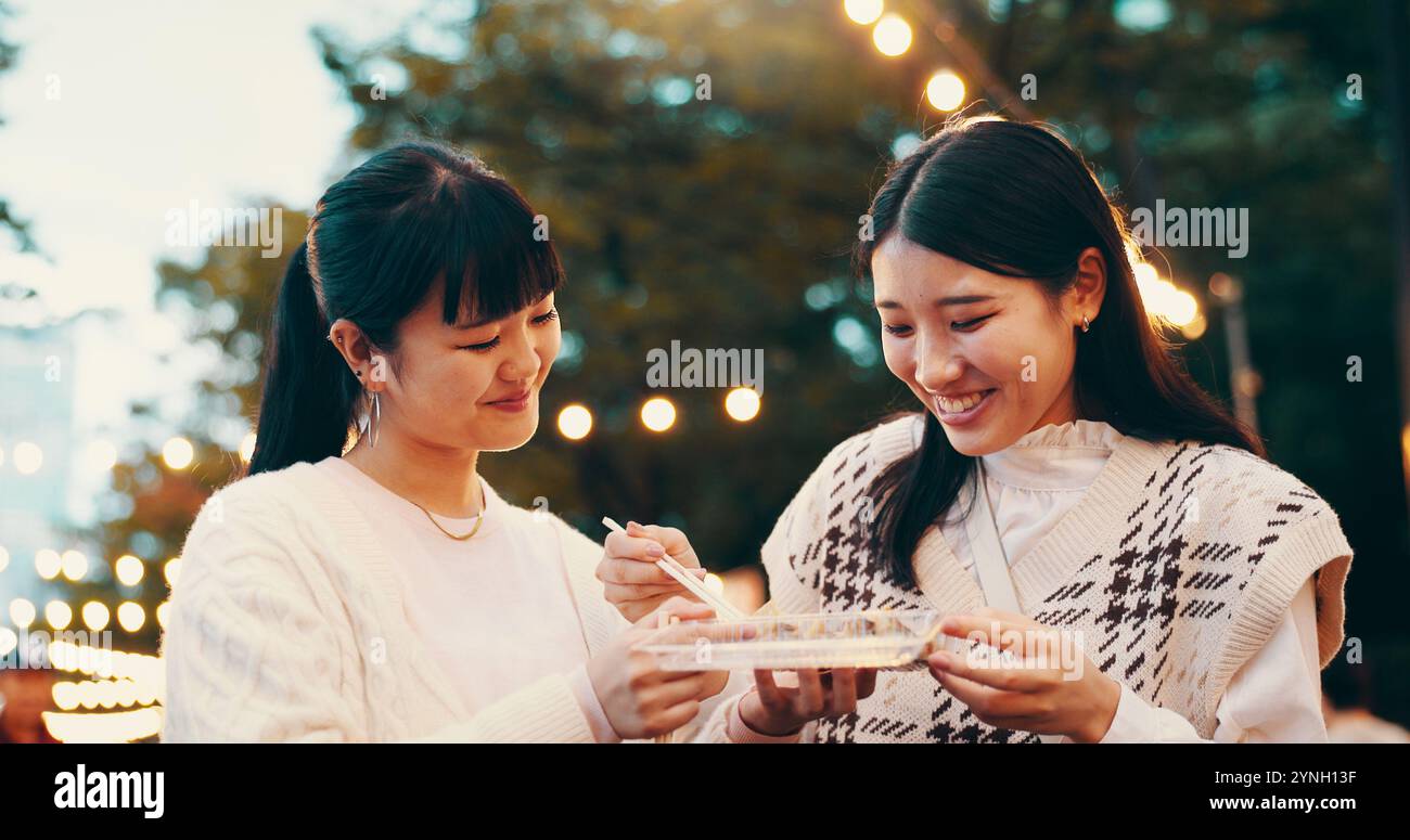 Ville, femmes asiatiques et étudiants avec bonbons, sourire et collation pour les amis avec dango, manger et voyager. Extérieur, friandises et bonbons pour la célébration de Banque D'Images