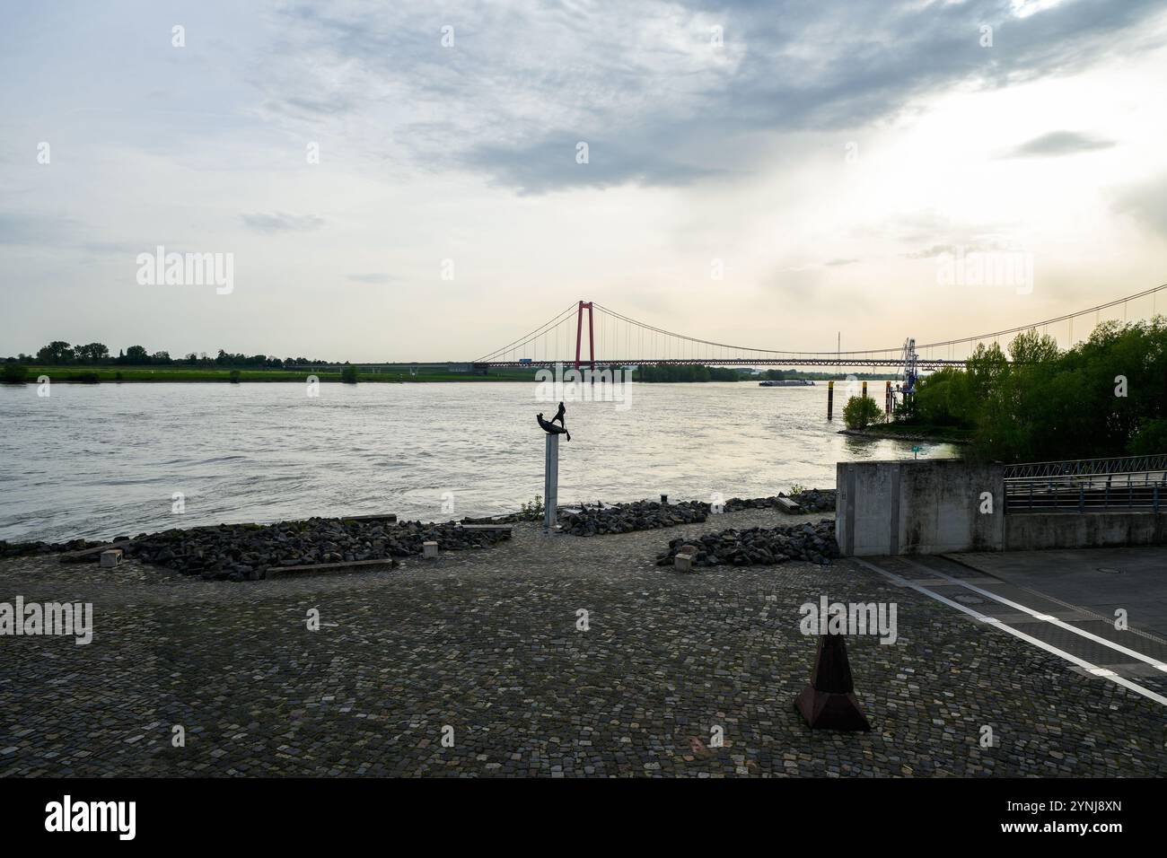 Vue sur le pont du Rhin près d'Emmerich am Rhein. Paysage au bord de la rivière dans la soirée avec un pont suspendu sur le Rhin inférieur. Banque D'Images