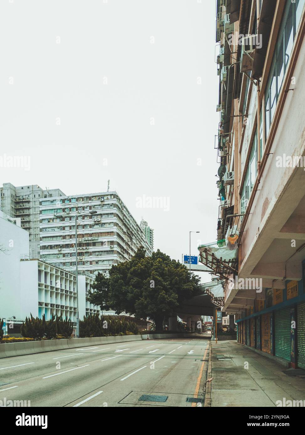 « Chemin urbain vide entouré de bâtiments résidentiels et commerciaux le jour couvert dans le paysage urbain du centre-ville » Banque D'Images