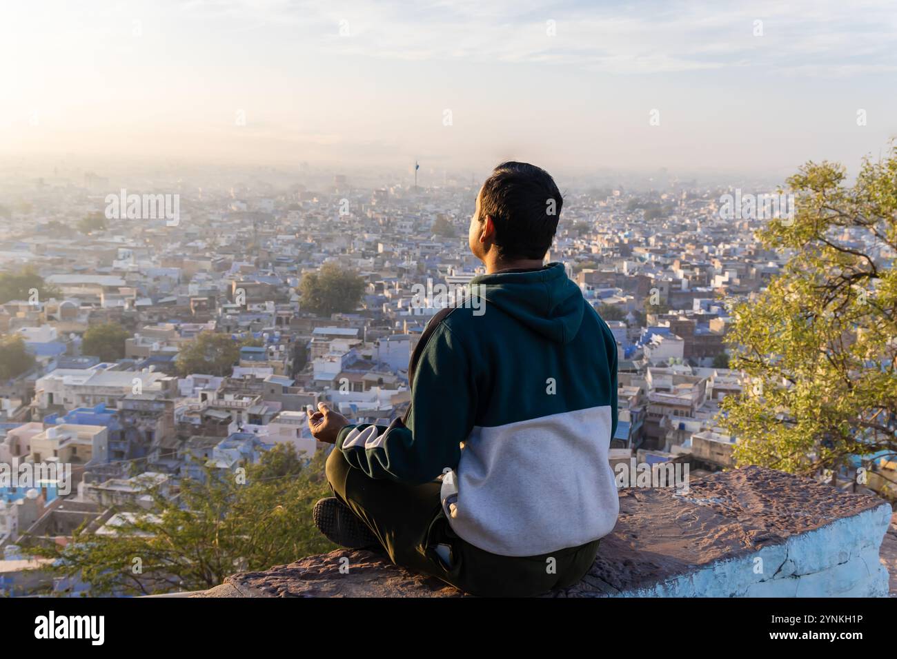 homme méditant au sommet de la montagne avec vue sur la ville au lever du soleil Banque D'Images