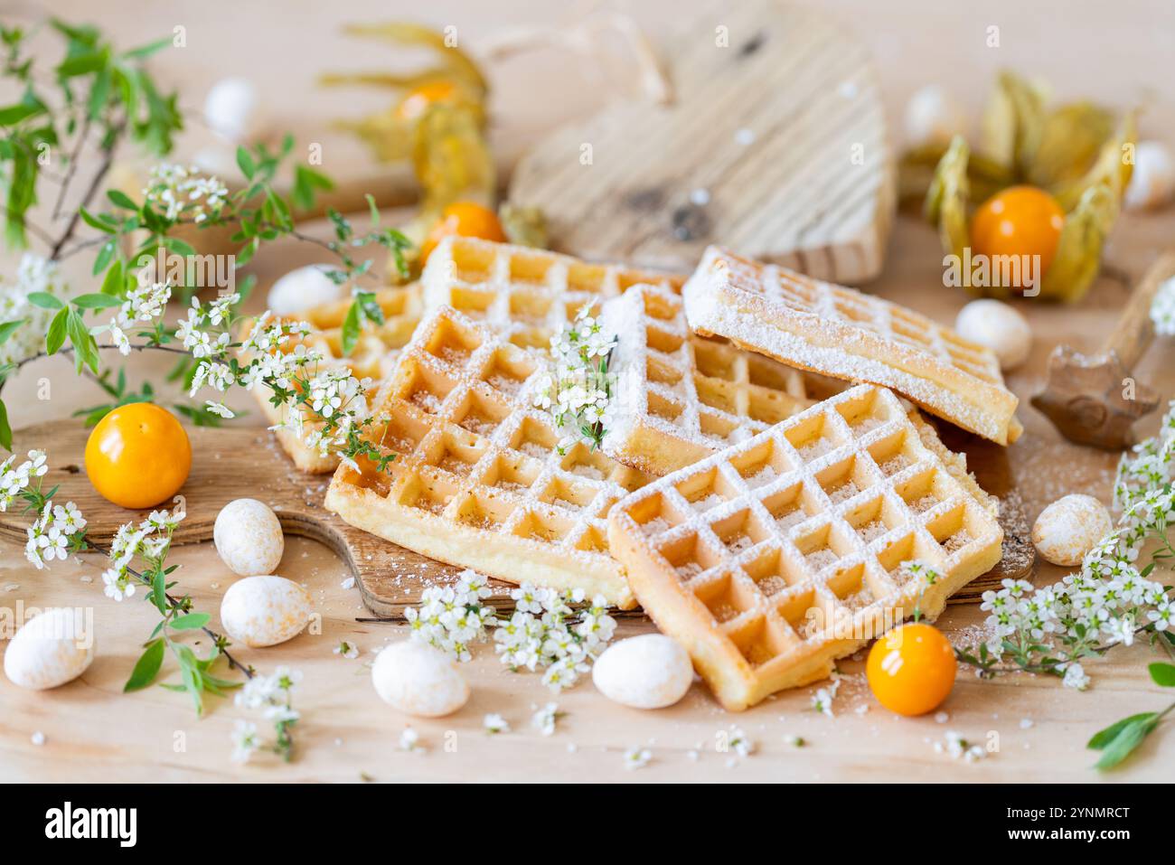 Gaufres avec sucre en poudre, fleurs de printemps et physalis – composition alimentaire rustique Banque D'Images
