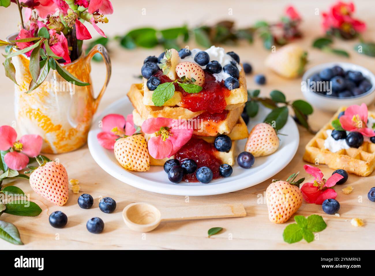Gaufres avec sucre en poudre, fleurs de printemps et physalis – composition alimentaire rustique Banque D'Images