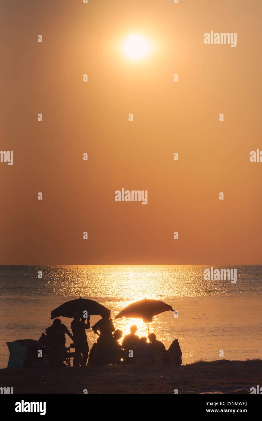 Coucher de soleil sur la plage et un groupe de personnes. Banque D'Images