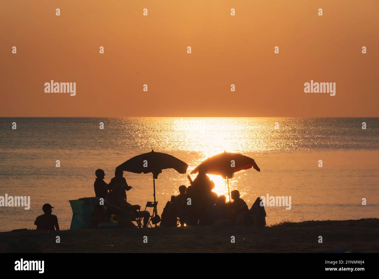 Coucher de soleil sur la plage et un groupe de personnes. Banque D'Images