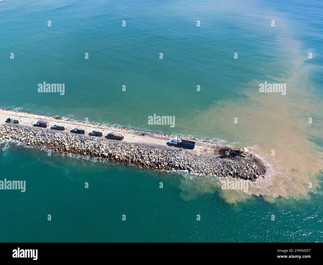 Camions et excavatrice faisant des travaux en mer aérienne au-dessus de la vue de drone de dessus Banque D'Images